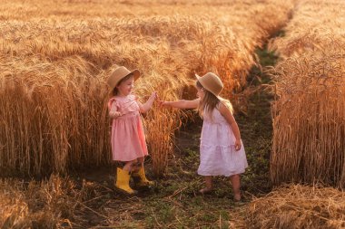 Hasır şapkalı ve pembe elbiseli iki küçük kız buğday tarlasında eğleniyor. Kız arkadaşlar birbirinin burnunu çavdar viskisiyle gıdıklıyor. Sarı lastik çizmeli abla, diğeri çamurda yalınayak.