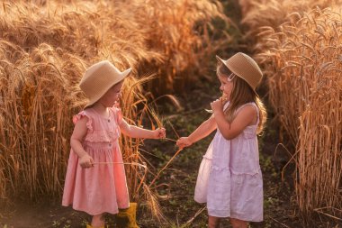 Hasır şapkalı ve pembe elbiseli iki küçük kız buğday tarlasında eğleniyor. Kız arkadaşlar birbirinin burnunu çavdar viskisiyle gıdıklıyor. Sarı lastik çizmeli abla, diğeri çamurda yalınayak.
