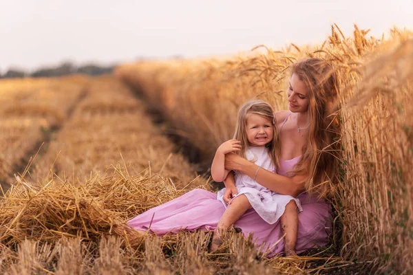 엄마와 황금빛 밀밭에 앉아서 재미를 있습니다 여자가 소녀를 즐겁게 간지럽힌다 — 스톡 사진