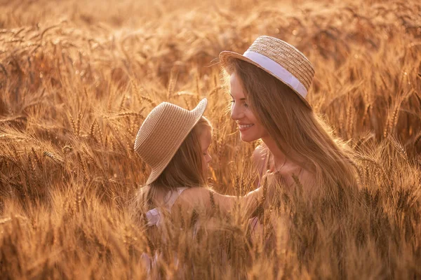麦畑のスライスでわら帽子の母親と娘のクローズアップ肖像画 小さな女の子がキスをし ライ麦の小穂に若い女性を抱きます 自然の農業のテクスチャ 女の子は楽しい 笑いを持っている — ストック写真
