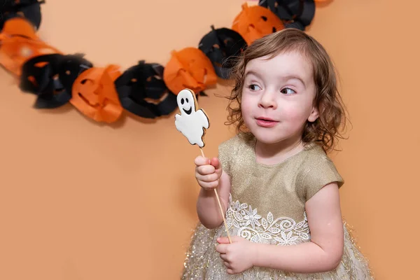 小女孩害怕鬼魂形式的姜饼饼干 在一个孤立的背景上用黑色和橙色南瓜的纸制花环做鬼脸很好玩 万圣节款待 复制空间 — 图库照片