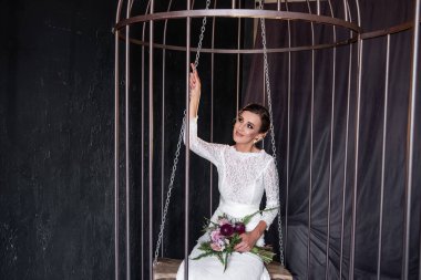 Moda gelini demir bir kafeste salıncakta oturup parmaklıkların arkasından dışarı bakıyor. Esaret altındaki altın kafesteki kuşun hayatı. Kadın haklarının ihlali. Uyduruk evlilik.