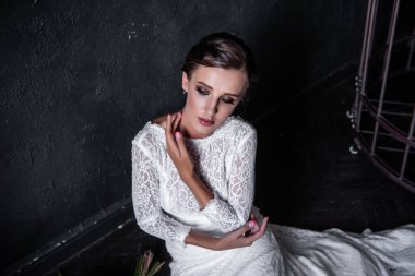 Duvaksız, beyaz bir elbise içinde demir bir kafesin, parmaklıkların arkasında oturan moda gelini. Mutsuz genç bir kadın, siyah dokulu bir geçmişi var. Hayali bir evlilik. Rahatlık düğünü. Boşluğu kopyala