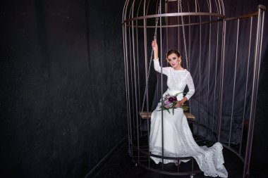 Moda gelini demir bir kafeste salıncakta oturup parmaklıkların arkasından dışarı bakıyor. Esaret altındaki altın kafesteki kuşun hayatı. Kadın haklarının ihlali. Uyduruk evlilik.