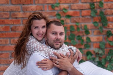 Birbirini seven birkaç milenyum kuşağı beyaz yatakta yeşil sarmaşıklı tuğla duvarın arka planına sarılıyor. Genç bir kadın, bir erkeği arkadan okşar, nazikçe öper. Aşıklar hafta sonu sabahları