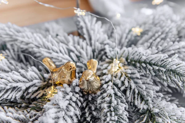 新年让金色的鸟儿在节庆的桌上 在雪地覆盖的圣诞树枝头之间嬉笑 斯堪的纳维亚风格的内部 表设置 假日奢侈装饰 复制空间 — 图库照片