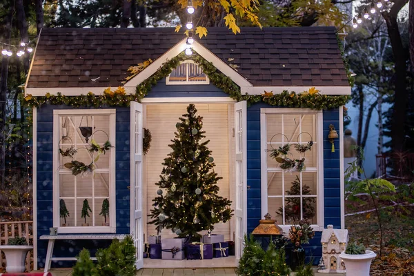 Bahçede şenlikli ahşap mavi bir ev var. Kapısında hediyeler olan Noel ağacı. Verandadaki Noel Baba için kırmızı postane. Çelenklerden yeni yıl çelengi. Kış zamanı.