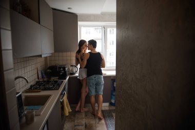 Siyah tişörtlü genç bir çift, sabahları mutfakta pencerede birbirine sarılan kot pantolonlar. Sevgili aşıklar kahvaltıdan önce eğlenirler. Erkekler kadınların saçlarını okşar. Yaşam tarzı apartman hayatı
