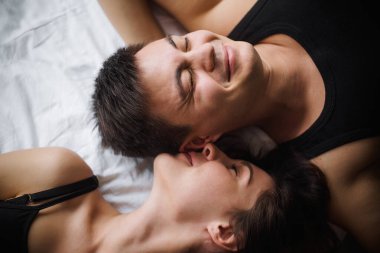 Birbirine aşık çiftlerin üst düzey görüntüsü. Evdeki yatakta tepeden tırnağa uzanan Aşıkların yakın plan portresi. Yeni evlilerin sabahı, evde şenlikli bir tatil gününde şefkatle dinleniyorlar. Dokunulmazlık kavramı