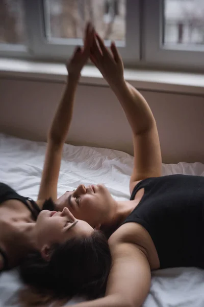 気にしないで 活動の概念 パートナーへの信頼 愛のカップルは ベッドの上に 足を笑って 自宅で抱擁にある 若い男はロフトの窓で女性とキスをする 恋人の手のタッチ — ストック写真