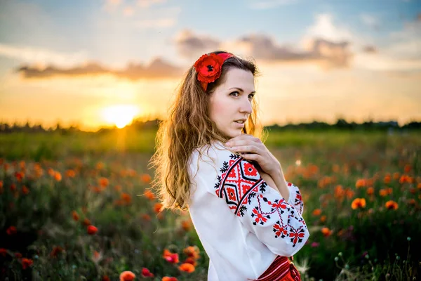 民族ウクライナの衣装刺繍シャツの若い女性のクローズアップ肖像画は日没時に赤いポピーの分野で踊っています 女の子の髪は明るい太陽の光の中で成長します 田舎の週末 — ストック写真