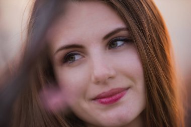 Günbatımında pembe çiçek açan Sakura bahçelerinde genç bir kadın. Şeftali çiçeği içindeki doğal güzel kızın yakın plan portresi. Şehir dışında yürüyüş, hafta sonları kırsal alanda. Boşluğu kopyala