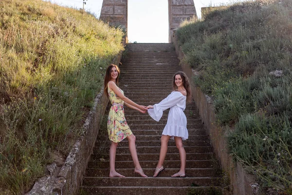 Дві Молоді Жінки Літніх Сукнях Тримають Один Одного Тлі Сходів — стокове фото