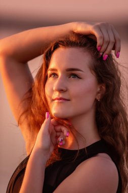 Kıvırcık, gün batımında havadar siyah elbiseli mutlu dansçının yakın plan portresi. Gölün sularındaki genç kadın deniz boyunca yürüyen gökyüzü yansımasıyla. Hayat tarzı seyahat hafta sonu. Sağlık, hareket kolaylığı