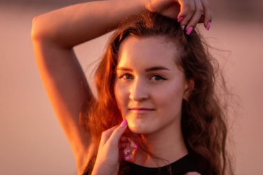 Kıvırcık, gün batımında havadar siyah elbiseli mutlu dansçının yakın plan portresi. Gölün sularındaki genç kadın deniz boyunca yürüyen gökyüzü yansımasıyla. Hayat tarzı seyahat hafta sonu. Sağlık, hareket kolaylığı