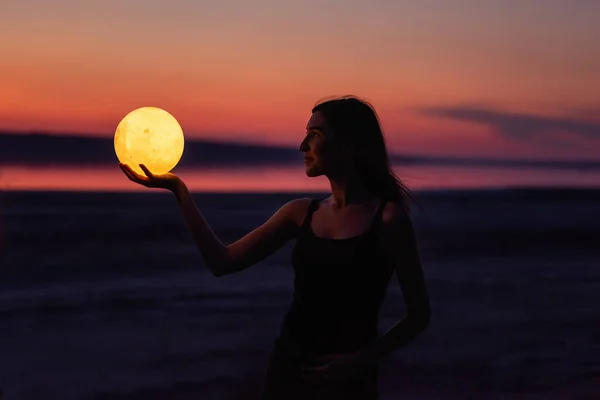 Young Woman Holds Full Moon Her Hands Backdrop Red Sunset — ストック写真