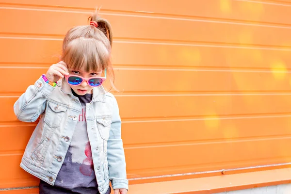 Emocjonalny Portret Małej Stylowej Dziewczynki Okularach Przeciwsłonecznych Pomarańczowym Tle Dziewczyna — Zdjęcie stockowe