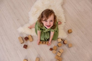 Elinde 2023 rakamları olan tahta küpleri tutan bir kız. Çocuk kulenin inşaatında oynuyor. Aktif ev oyunları. Yaşam tarzı çocuk eğitimi konsepti. Boşluğu kopyala, kapat