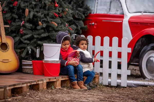 Afroamerykańskie Dzieci Zimowych Ciuchach Siedzą Drewnianych Paletach Przy Choince Otwierając — Zdjęcie stockowe