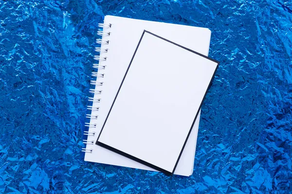 Bakgrund av blå skrynklig folie. Tomma blad av vitt papper. — Stockfoto