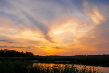 Gün batımında Lielupe Nehri 'nde. Parlak, renkli gökyüzü, turuncu, sarı, bulutların altın rengi.