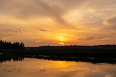 Gün batımında Lielupe Nehri. - Letonya. Parlak, renkli gökyüzü, bulutların altın rengi..