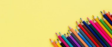 Sarı arka planda renkli tahta kalemli pankart yakın planda. Kopya alanı olan renkli kalemler. en üstteki görünüm.