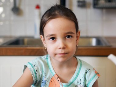 Çocukların bağımsızlığı fikri ve mutfak aletlerini kullanabilme yeteneği. Masanın mutfağında altı yaşında bir kızın portresi. Yakın plan..