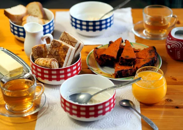 キッチンテーブルの上にバター、焼きカボチャ、牛乳麺と蜂蜜茶と控えめな食事の朝食. — ストック写真