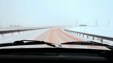 Hareket halindeki bir arabadan ön cama doğru yol manzarası. Kış, kar, yol ve yaklaşan arabalar..