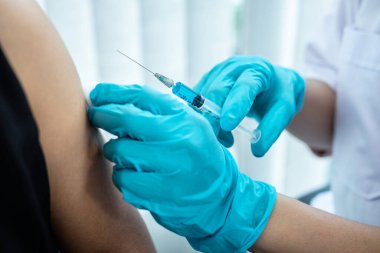 Doktor iğneyle hastaya aşı yapıyor. Grip aşısı için koluna bağışıklık aşısı yaptırıyor. Salgına karşı koronavirüs koruyucu..