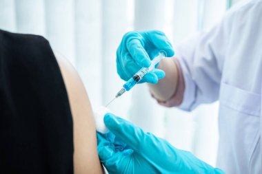 Doktor iğneyle hastaya aşı yapıyor. Grip aşısı için koluna bağışıklık aşısı yaptırıyor. Salgına karşı koronavirüs koruyucu..
