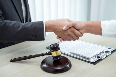 Erkek avukat, iyi bir müzakere işbirliği toplantısı sonrasında müvekkille tokalaşıyor..