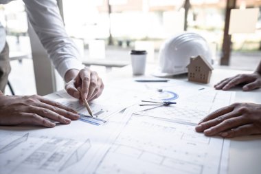 Mimarlar veya mühendislik ekibi, modern ofisteki tasarım ve model ev üzerine yeni mimari projeler planlayan nesneler, araçlar ve inşaat çizimleri üzerinde danışmanlık ve analiz yapıyor..