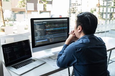 IT şirketinin ofisindeki yazılım geliştirme bilgisayarında proje üzerinde çalışan geliştirici programcısı, sorunlara çözüm bulmak için kodlar ve veri kodu web sitesi ve kodlama veritabanı teknolojileri.