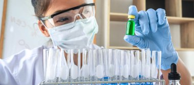 Laboratuvarda virüs ve aşı antiretroviral koronavirüs hakkında çalışan kadın araştırmacı ya da doktor test tüpleri ve mavi sıvı çözeltisi ile araştırma yapıyor..
