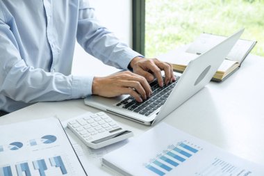 Bilgisayarda grafik üzerinde çalışan genç iş adamı ya da muhasebeci, veri istatistiklerini ve hesap makinesini analiz ederek pazarlama araştırma planlama raporunu sunar..