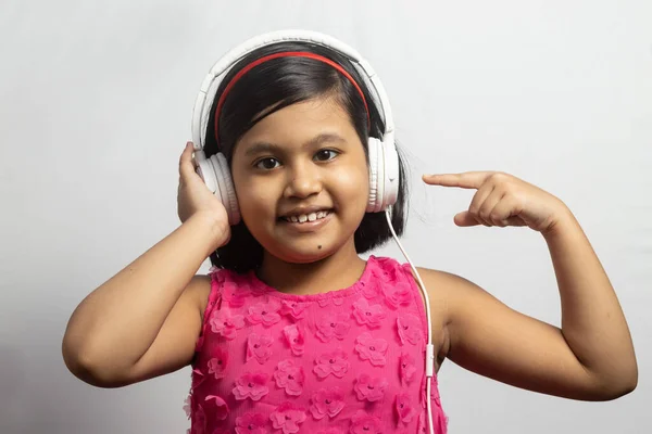 Słodkie Indyjskie Dziecko Dziewczyna Słuchanie Muzyki Dotykając Wskazując Biały Słuchawki — Zdjęcie stockowe