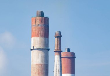 Mavi gökyüzü arkaplanındaki bacaların ya da duman yığınlarının görüntüsünü kapat
