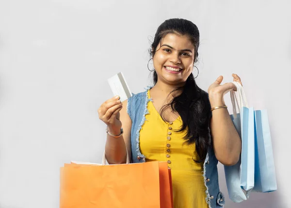 白い背景にショッピングバッグやクレジットカードで黄色のドレスの美しいインドの女性 — ストック写真