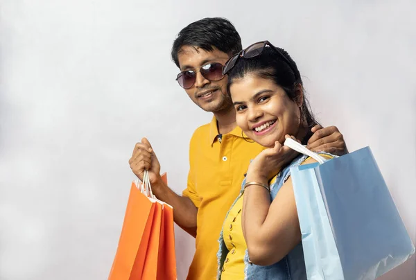 インドのカップルで黄色のドレスでショッピングバッグ笑顔で白い背景 — ストック写真