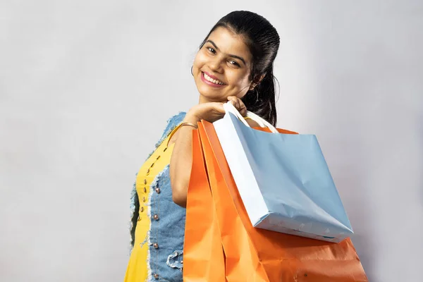 白い背景にカメラを見てショッピングバッグと黄色のドレスの美しいインド人女性 — ストック写真