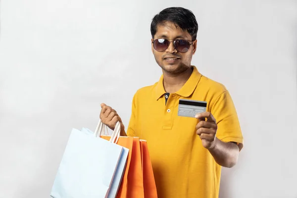 中年インド人男性で黄色のドレスでショッピングバッグとクレジットカード笑顔でカメラで白い背景 — ストック写真