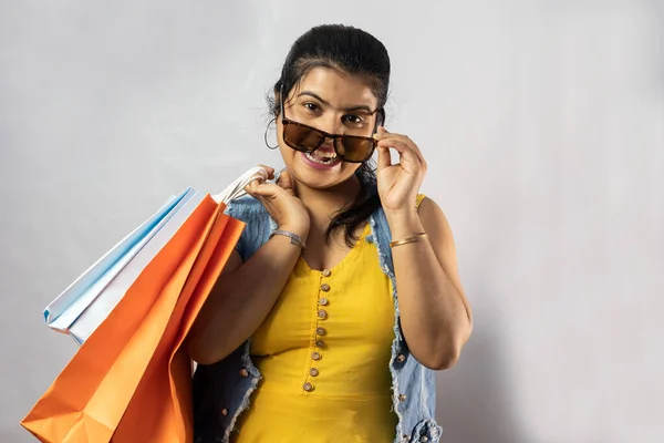 白い背景にショッピングバッグと大きな笑顔と黄色のドレスの美しいインド人女性 — ストック写真
