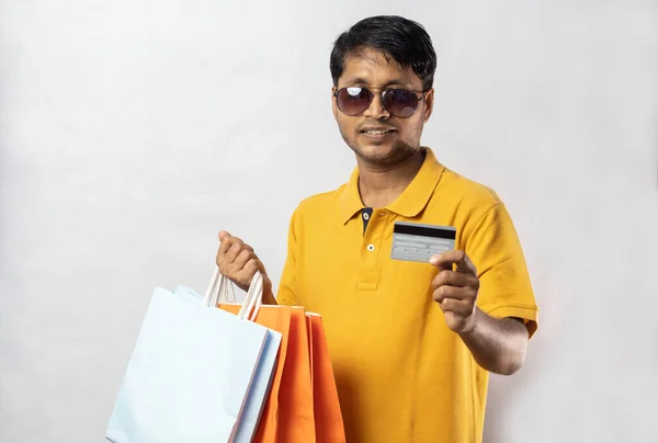中年インド人男性で黄色のドレスでショッピングバッグとクレジットカード笑顔でカメラで白い背景 — ストック写真