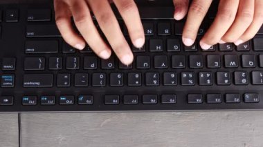 Masaüstü bilgisayarının klavyesini yazan Hintli bir adamın ellerinin üst görünümü
