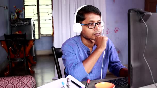 身穿蓝色衣服的印度男子在家里的电脑前工作 他带着耳机和视频打电话 — 图库视频影像