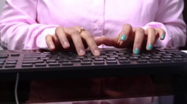 Masaüstü bilgisayarının klavyesini yazan Hintli bir kadının orta bölüm görünümü