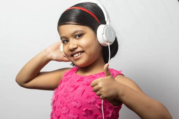 Słodkie Indyjskie Dziecko Dziewczyna Słuchanie Muzyki Dotykając Biały Słuchawki Pokazując — Zdjęcie stockowe