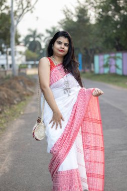 Kırmızı sarili, uzun saçlı, kameraya poz veren güzel bir Hintli kadın.